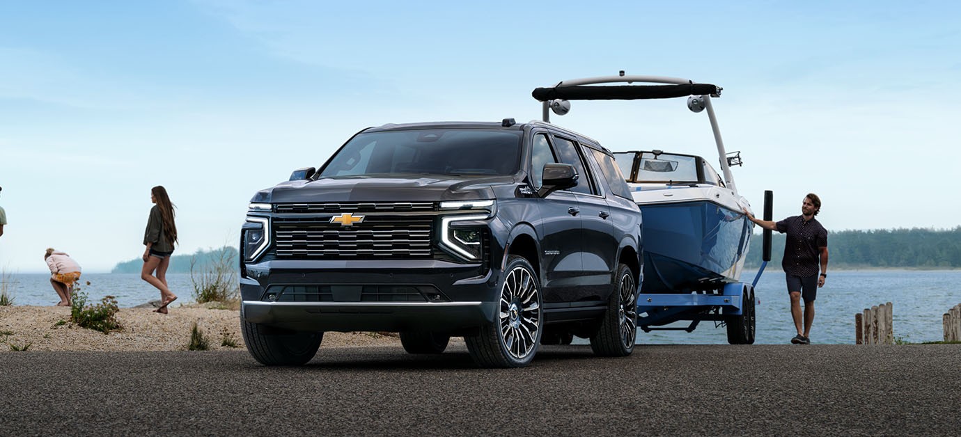 2026 Chevrolet Suburban full-size SUV ready for outdoor recreation with a boat in tow.